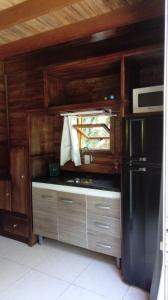 a kitchen with a black refrigerator and wooden cabinets at Tiny House II - Sítio dos Wolff in Gravataí
