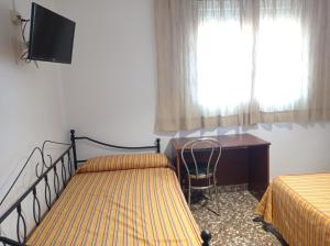 - une chambre avec 2 lits, un bureau et une télévision dans l'établissement Antolin Guest House, à Minaya