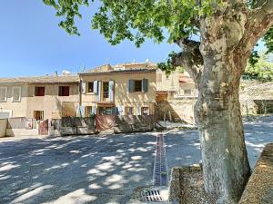 a house with a tree next to a street at T2 Robion luberon in Robion en Luberon