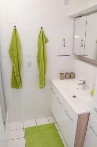 a white bathroom with green towels on the wall at Voitsberg-Apartments in Voitsberg