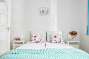 a white bedroom with a bed with blue sheets and pillows at Szarka Vendégház és Pince in Mád