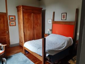 1 dormitorio con 1 cama con cabecero naranja en Le Logis, en Les Pineaux