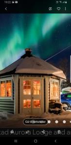 a small house with a green northern lights in the sky at Villa Myklebostad in Breidvika