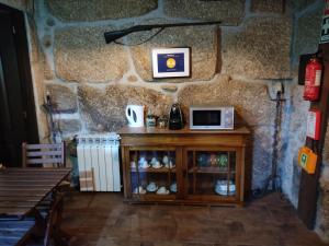 a table with a microwave on top of a stone wall at Lagar da Silveira in Penafiel