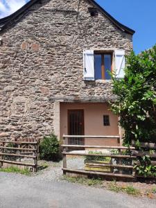 ein Steinhaus mit einem Fenster und einem Zaun in der Unterkunft les gites de la bouldoire Renaissance in Rignac