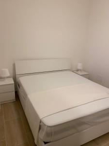 ein weißes Bett in einem weißen Zimmer mit zwei Nachttischen in der Unterkunft Casetta Roca in Roca Vecchia