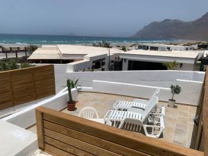 a balcony with white chairs and a view of the ocean at Apartment in Famara Beach in Teguise