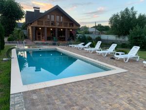 a swimming pool with lounge chairs and a house at Le RoSA in Brailiv