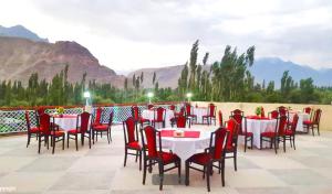 ein Restaurant mit Tischen und Stühlen mit Bergen im Hintergrund in der Unterkunft Baltistan Continental Hotel Skardu Pakistan in Skardu