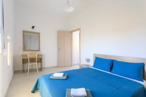 a bedroom with a blue bed and a desk at Palm Studios in Perissa +21 photos