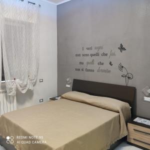 カステッランマーレ・ディ・スタービアにあるL'acchiappasogni casa vacanzeのベッドルーム1室(壁に文字が付いたベッド1台付)