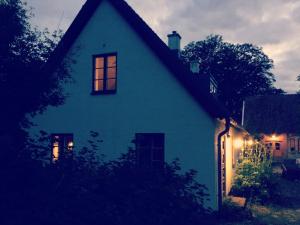 una casa azul con luces en la ventana por la noche en Gladeholm en Kivik