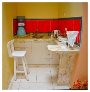 a small kitchen with red cabinets and a counter at Hospedaje La Casa Blanca in Urbanizacion Buenos Aires