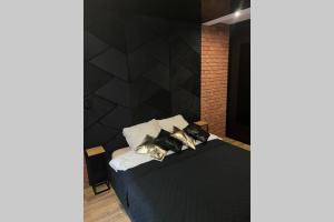 - une chambre dotée d'un mur noir et d'un lit avec des oreillers dans l'établissement Apartament Manufaktura z bezpłatnym parkingiem, à Łódź