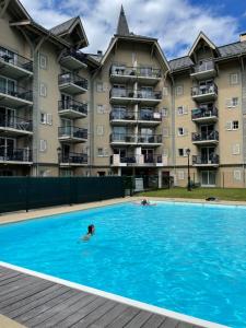 - un groupe de personnes se baignant dans une piscine en face d'un bâtiment dans l'établissement Appartement 6 personnes Grand Panorama, à Saint-Gervais-les-Bains