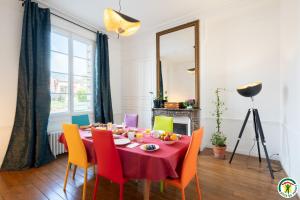 a dining room with a table with colorful chairs at Chez Hortense in Beauvais