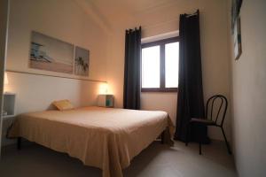 a bedroom with a bed and a window and a chair at Sea View Vista Mare - Soggiorni settimanali da sabato a sabato in Isola Capo Rizzuto