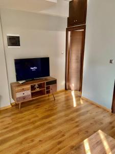 a living room with a tv and a wooden floor at Modern Apartment in the heart Vol2 in Alexandroupoli