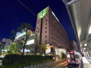 a tall building with a train in front of it at APA Hotel Ogaki Ekimae in Ogaki