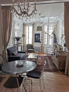 een woonkamer met een kroonluchter en een tafel en stoelen bij Les Papillons de St Leonard in Honfleur