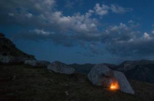 a fire sitting on top of a mountain at night at Guesthouse Letnja Basta in Lukomir