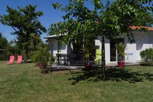 Jolie Villa neuve, au calme, proche forêt / Bisca في بيسكاروس: بيت أبيض وكراسي حمراء في ساحة
