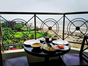 a table with food on a balcony with a view of the beach at Suite Sadaf in Cox's Bazar