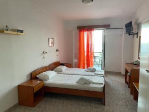sypialnia z 2 łóżkami i pomarańczową zasłoną w obiekcie Apollon Hotel w mieście Methana