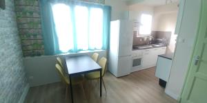 a kitchen with a table and chairs and a refrigerator at Appartement 3 chambres très fonctionnel sud Grenoble in Grenoble