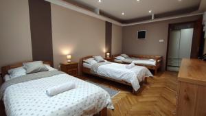 a bedroom with two beds with white sheets and wooden floors at Lux Apartman Velence in Velence