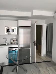 a kitchen with a stainless steel refrigerator and a glass table at Apart 3 EN PRIMERA LÍNEA DE PLAYA CON TERRAZA Y VISTAS AL MAR in Almería