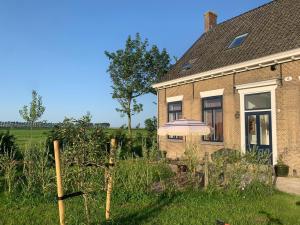 une maison en briques avec un parasol dans la cour dans l'établissement Huisje op Bioboerderij, kust, polder en rust, à Hoofdplaat