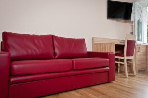 ein rotes Sofa im Wohnzimmer mit einem Tisch in der Unterkunft Bergrestaurant Schwedenstein in Steina