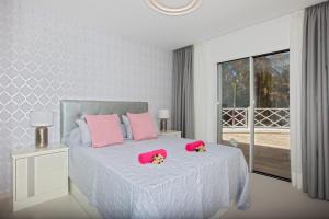 een witte slaapkamer met een wit bed met roze kussens bij PLAYA CHICA by Buenavilla in Puerto del Carmen