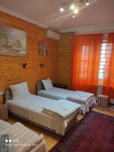 two beds in a room with wooden walls at Sobe sa sopstvenim KUPATILOM Private rooms bathroom In CENTER in Novi Sad
