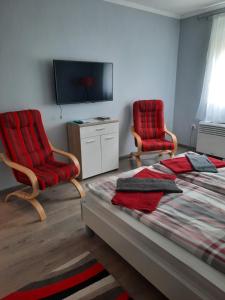 エゲルにあるKodály Apartmanのベッドルーム1室(椅子2脚、ベッド1台、テレビ付)