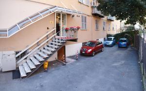 un edificio de apartamentos con una escalera y coches aparcados en un aparcamiento en Hotel Boccascena en Génova