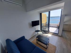 a living room with a blue couch and a large window at Panorama Apartments in Herceg-Novi
