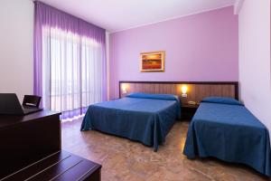 two beds in a room with purple walls at Hotel Belvedere in Porto SantʼElpidio