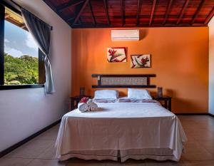 een slaapkamer met een bed met oranje muren en een raam bij Areia Branca Apart Hotel in Morro de São Paulo