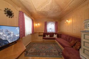 a living room with a couch and a tv at Chalet Merisana in Selva di Val Gardena