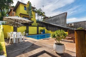 a patio with a table and chairs and an umbrella at Areia Branca Apart Hotel in Morro de São Paulo