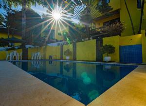 a swimming pool with the sun in the background at Areia Branca Apart Hotel in Morro de São Paulo