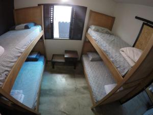 three bunk beds in a room with a window at Like a Hostel in Poços de Caldas