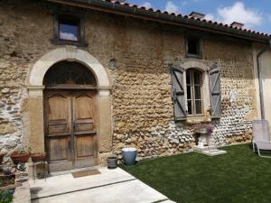 een stenen huis met een houten deur en een tuin bij Hello Pyrenees in Castelvieilh