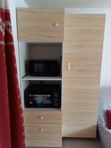 a wooden cabinet with a microwave in a room at Studio 4 personnes centre Superbesse in Super Besse +8 photos