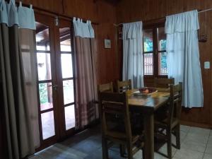 a dining room with a table and chairs and windows at Iguazú Cabañas in Puerto Iguazú