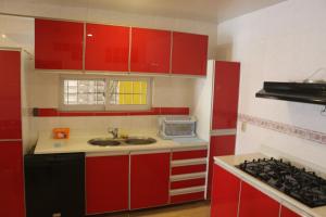 cocina roja con fregadero y fogones en Compleet vrijstaand woonhuis Paramaribo, en Paramaribo