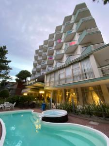un hôtel avec une piscine en face d'un bâtiment dans l'établissement Hotel Monaco, à Milano Marittima