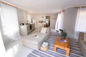 a living room with a couch and a table at Spacious and light Kalk Bay Garden Apartment in Kalk Bay